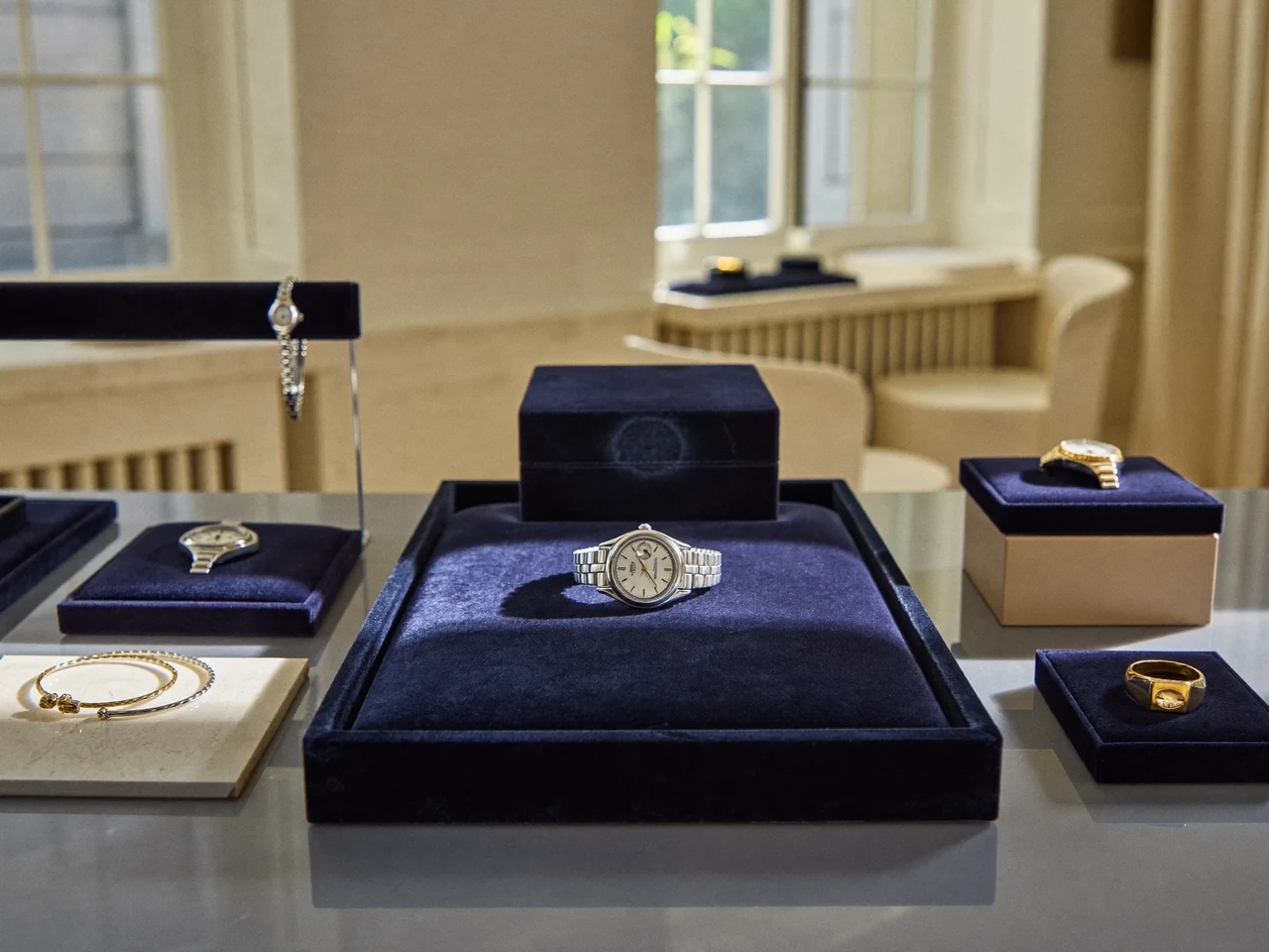 Helle Boutique-Auslage mit Armbanduhren und Ringen auf dunklen Samtablagen